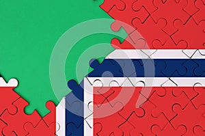 Norway flag is depicted on a completed jigsaw puzzle with free green copy space on the left side