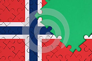 Norway flag is depicted on a completed jigsaw puzzle with free green copy space on the right side