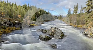 Roaring white water running down the river in autumn in Norway