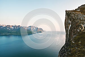 Norway landscape man standing on cliff rock edge above fjord Senja mountains travel hiking adventure