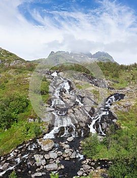 Norway Lofoten Moskenes waterfall with mountain in the background. Beautiful summer panorama.