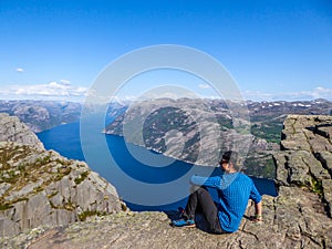 Norway - A man sitting at the edge of Preikestolen