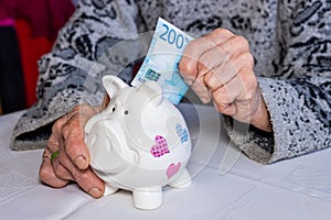 Norway money, Pensioner puts 200 Norwegian kroner into a piggy bank, financial concept, Saving and financial security of elderly