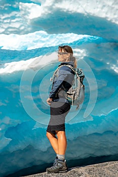 Norway Travel, Young Woman with a backpack admires Nigardsbreen Nigar Glacier arm of Jostedalsbreen located in Gaupne Jostedalen