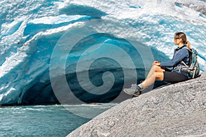 Norway Travel, Young Woman with a backpack admires Nigardsbreen Nigar Glacier arm of Jostedalsbreen located in Gaupne Jostedalen