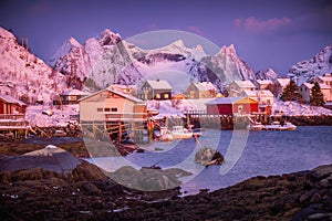 Norwegian fishing village with red rorbu houses, mountain peaks and sea coast winter landscape, Lofoten islands, Norway