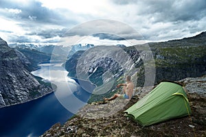 Norwegian fjord landscape with camping tent and young traveller. peace of mind concept