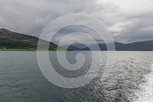 Norwegian fjord and mountains surrounded by clouds, ideal fjord reflection in clear water. selective focus