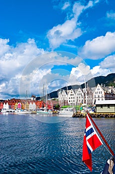 Norwegian flag on the background of the bay and the old wooden houses on the waterfront of Bergen