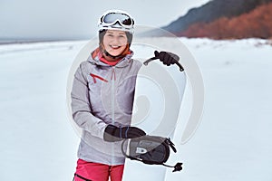 Norwegian girl wearing warm snowboard suit, posing with her snowboard