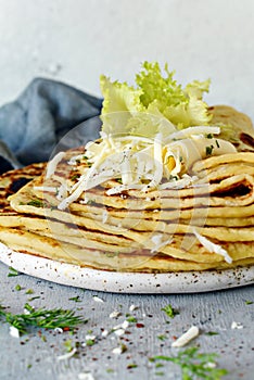 Norwegian potato pancakes Lefse on a light background with cheese and greens.