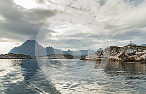 Norwegian seascape, lighthouse on the island, rocky coast with dramatic skies, the sun breaks through the clouds, sheer