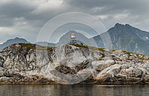 Norwegian seascape, lighthouse on the island, rocky coast with dramatic skies, the sun breaks through the clouds, sheer