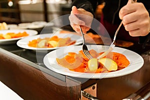 Norwegian Smoked Salmon fillet table side served with lemon by woman hands with forks. Seafood appetizer menu.