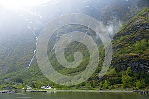 Norwegian village in Fjord with waterfalls in the background