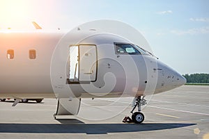 Nose and cockpit of a white passenger jet in the airport parking lot. Passenger aircraft, white airplane without livery