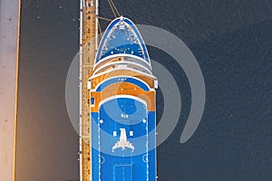 Nose of a cruise passenger liner at the pier in the river port, aerial top view