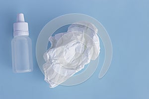 Nose drops and crumpled tissue on a blue background, the concept of colds, infections, rhinitis