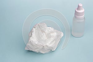 Nose drops and crumpled tissue on a blue background, the concept of colds, infections, rhinitis