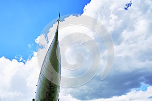 The nose of the plane on the background of the blue sky with clouds copy space