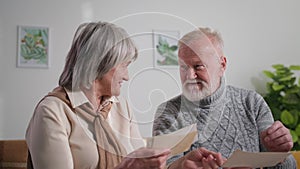 nostalgia, happy elderly family couple enjoy memories, gray-haired man and woman looking at old album with photos at