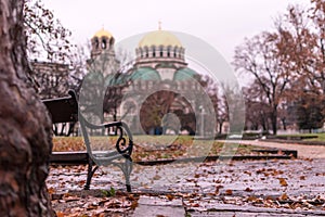 Nostalgic autumn view with a benach and the Alexander Nevsky Orthodox Christian Cathedral in Sofia, Bulgaria, in the background