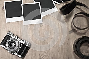 Nostalgic concept blank instant photo frames on wooden background with old retro vintage camera with film strip and copy space