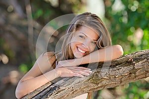 Nostalgic moments of a beautiful girl as she rests on a tree trunk