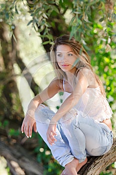 Nostalgic moments of a beautiful girl as she rests on a tree trunk