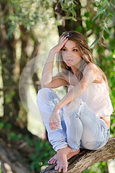 Nostalgic moments of a beautiful girl as she rests on a tree trunk