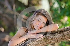 Nostalgic moments of a beautiful girl as she rests on a tree trunk