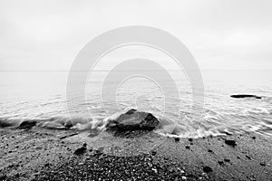 Nostalgic sea. Waves hitting in rock in the center. Black and white