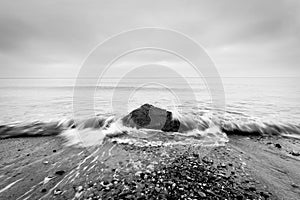 Nostalgic sea. Waves hitting in rock in the center. Black and white