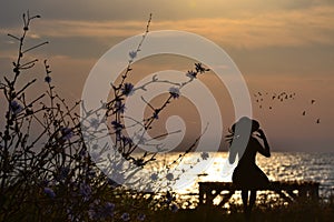 Nostalgic woman siting on a bench by the sea photo