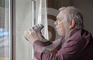 Nosy neighbor looking out of window with binoculars