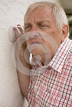 Nosy neighbour holding a glass up to the wall