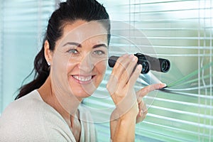 nosy woman peering through blinds