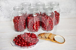 Not closed glass jars with cherries, prepared for canning with tin screw lids