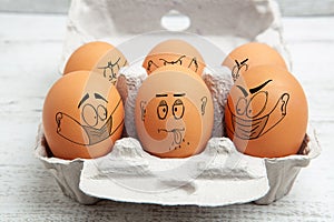 Not complying with social distancing rules and wearing face mask in public - concept depicted with faces illustrated on eggs. photo