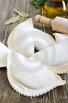 Not fried chebureks in flour on a wooden table. Traditional Turkic-Mongolian dish. photo