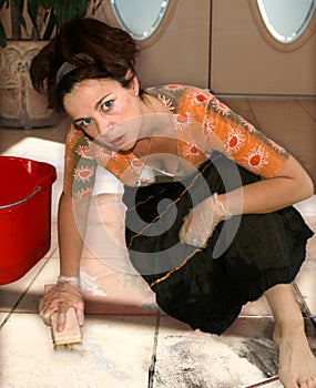 Donna di mezza età alla ricerca infelice, mentre lo scrubbing un pavimento sporco.