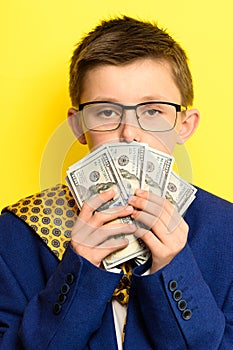 Not a lot of adult child, financially literate boy, money in the hands of a child, portrait on a yellow background.