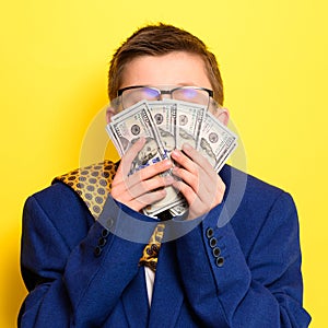 Not a lot of adult child, financially literate boy, money in the hands of a child, portrait on a yellow background.