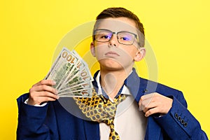 Not a lot of adult child, financially literate boy, money in the hands of a child, portrait on a yellow background.