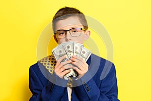Not a lot of adult child, financially literate boy, money in the hands of a child, portrait on a yellow background.