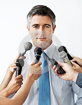 Not saying more than he has too...Handsome mature businessman being interviewed against a white background.