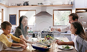 Not only sharing food but love as well. two affectionate young parents having a meal with their kids in the kitchen at