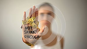 Not skinny enough written on woman palm with tape, severe diet, anorexia
