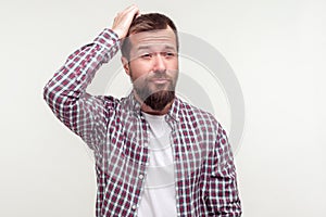 Not sure, don`t know! Portrait of confused bearded man in plaid shirt scratching head. isolated on white background