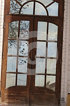 Not very clean glass doors reflect the roof of the building and the surrounding nature.